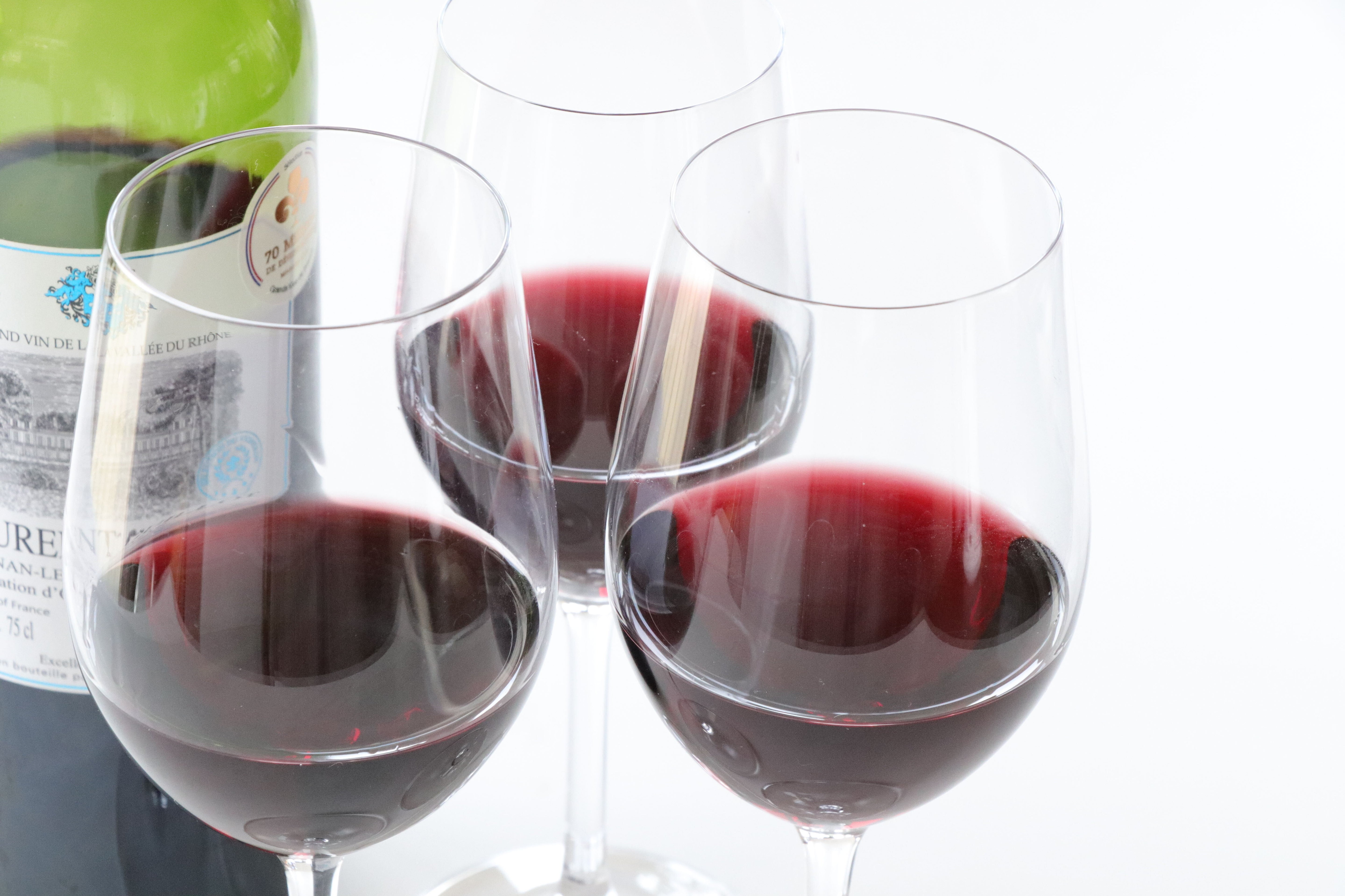 赤ワインが注がれたグラスが3つと、ボトルが並んでいる